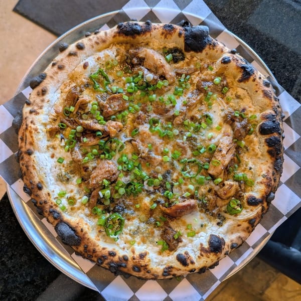 Pop-Start Pizza's chicken pizza with white sauce, green onions, and a charred crust.