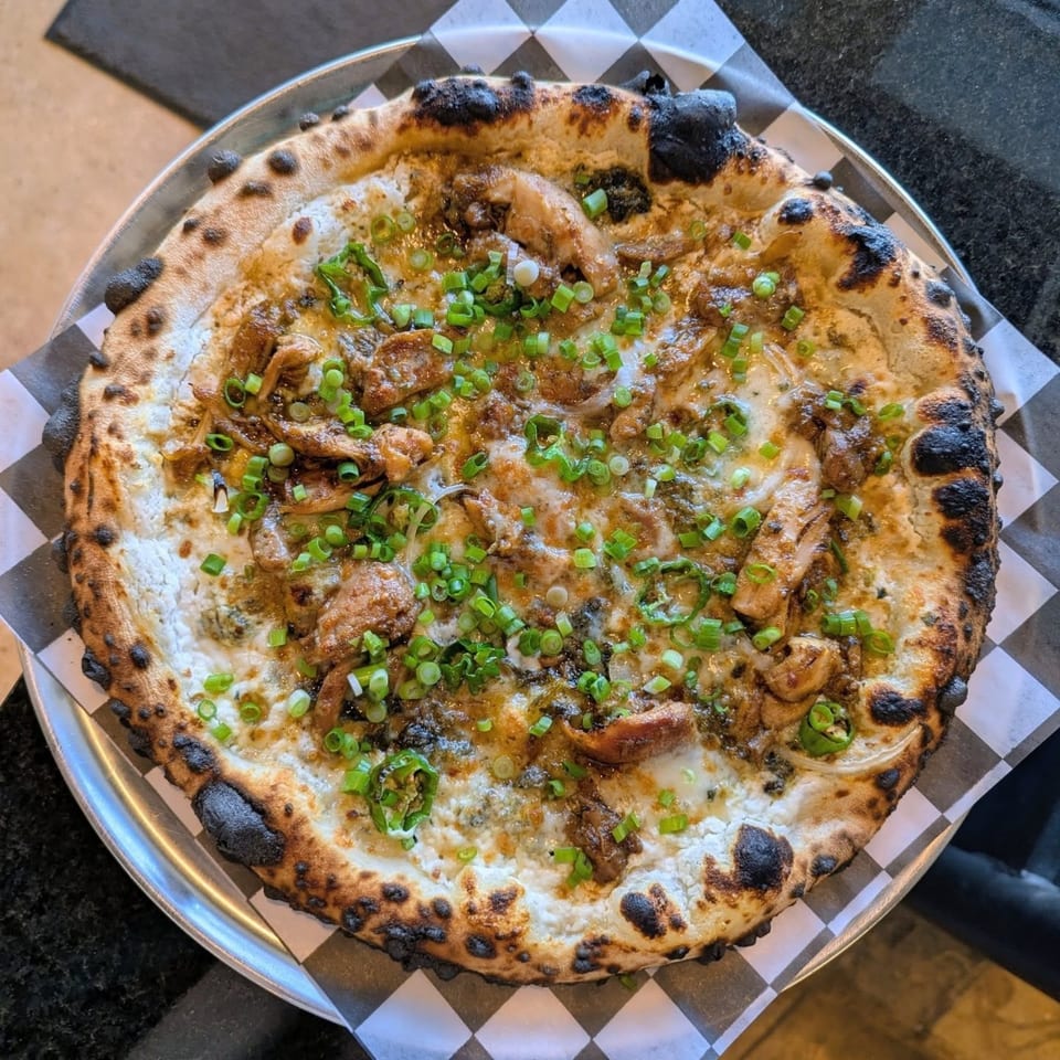 Pop-Start Pizza's chicken pizza with white sauce, green onions, and a charred crust.